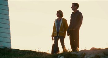 A man and a woman standing next to each other on top of a hill
