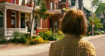 Movie still from “Take This Waltz” (2011), directed by Sarah Polley – A woman in a yellow and white checkered shirt looking at a house; Medium shot, Over the shoulder angle