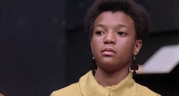 Movie still from “Taking Off” (1971), directed by Milos Forman – A young woman wearing a yellow shirt and earrings; Close Up shot, Low angle