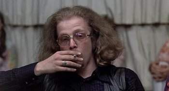Movie still from “Taking Off” (1971), directed by Milos Forman – A man with long hair and glasses smoking a cigarette; Close Up shot, Low angle