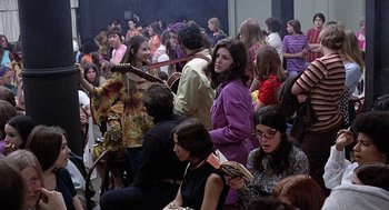 Movie still from “Taking Off” (1971), directed by Milos Forman – A group of people sitting in a room with a guitar; Wide shot, High angle
