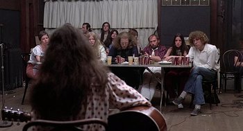 Movie still from “Taking Off” (1971), directed by Milos Forman – A group of people sitting at a table with drinks; Wide shot, Over the shoulder angle