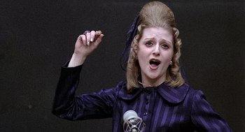 Movie still from “Taking Off” (1971), directed by Milos Forman – A woman in a purple dress holding a microphone and singing; Close Up shot, Low angle