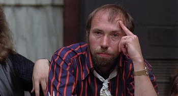 Movie still from “Taking Off” (1971), directed by Milos Forman – A man with a beard and a striped shirt; Close Up shot, Over the shoulder angle