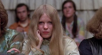 Movie still from “Taking Off” (1971), directed by Milos Forman – A woman sitting in front of a group of other people; Close Up shot, Low angle