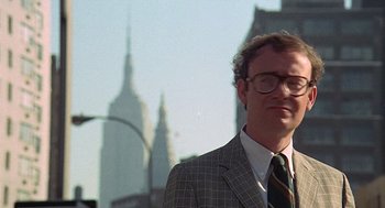 Movie still from “Taking Off” (1971), directed by Milos Forman – A man in a suit and tie standing in front of a building; Close Up shot, Low angle
