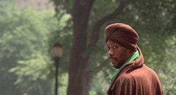 Movie still from “Taking Off” (1971), directed by Milos Forman – A man with a turban is standing in a park; Close Up shot, Over the shoulder angle