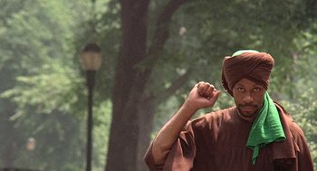 Movie still from “Taking Off” (1971), directed by Milos Forman – A man in a turban is standing in a park; Medium shot, Low angle