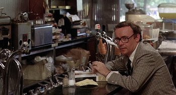 Movie still from “Taking Off” (1971), directed by Milos Forman – A man sitting at a table in front of a computer; Medium shot, Over the shoulder angle