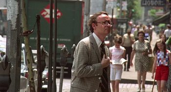 Movie still from “Taking Off” (1971), directed by Milos Forman – A man walking down the street wearing a suit and tie; Medium shot, Over the shoulder angle