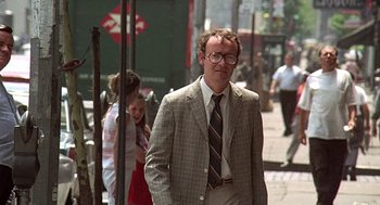 Movie still from “Taking Off” (1971), directed by Milos Forman – A man wearing a suit and tie walking down a street; Medium shot, Over the shoulder angle