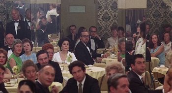 Movie still from “Taking Off” (1971), directed by Milos Forman – A group of people sitting at a dinner table; Medium shot, Over the shoulder angle