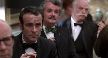 Movie still from “Taking Off” (1971), directed by Milos Forman – A group of men in suits and bow ties standing next to each other; Close Up shot, Over the shoulder angle