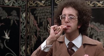 Movie still from “Taking Off” (1971), directed by Milos Forman – A man in a suit and tie eating a piece of food; Close Up shot, Low angle