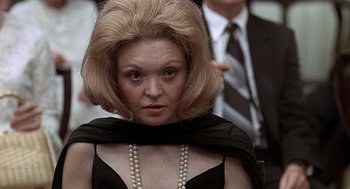 Movie still from “Taking Off” (1971), directed by Milos Forman – A person wearing a black dress and pearls; Close Up shot, Low angle