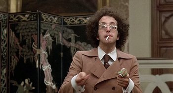 Movie still from “Taking Off” (1971), directed by Milos Forman – A man in a brown suit smoking a cigarette; Medium shot, Low angle