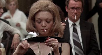 Movie still from “Taking Off” (1971), directed by Milos Forman – A woman smoking a cigarette while wearing a dress; Close Up shot, Over the shoulder angle