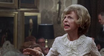 Movie still from “Taking Off” (1971), directed by Milos Forman – An older woman in a white dress talking to people; Close Up shot, Over the shoulder angle