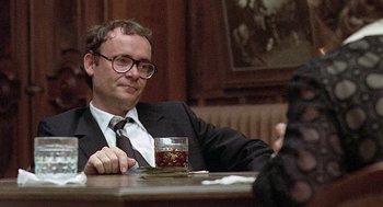 Movie still from “Taking Off” (1971), directed by Milos Forman – A man sitting at a table with a glass of whiskey; Close Up shot, Over the shoulder angle