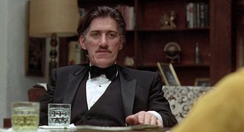 Movie still from “Taking Off” (1971), directed by Milos Forman – A man sitting at a table with a glass of water in front of him; Close Up shot, Low angle