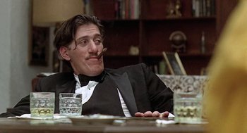 Movie still from “Taking Off” (1971), directed by Milos Forman – A man sitting at a table with a cigar in his mouth; Close Up shot, Low angle