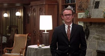 Movie still from “Taking Off” (1971), directed by Milos Forman – A man in a suit and tie standing in front of a table; Medium shot, Low angle