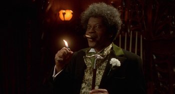 Movie still from “Tales from the Hood” (1995), directed by Rusty Cundieff – A man in a suit and tie holding a lit candle; Medium shot, Low angle