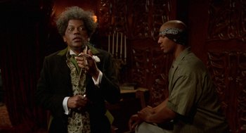 Movie still from “Tales from the Hood” (1995), directed by Rusty Cundieff – Two men are sitting in a room talking to each other; Medium shot, Low angle