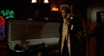 Movie still from “Tales from the Hood” (1995), directed by Rusty Cundieff – A man in a black jacket is pointing to something on the ground; Medium shot, Low angle