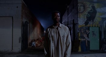 Movie still from “Tales from the Hood” (1995), directed by Rusty Cundieff – A man standing in the dark in front of a building; Medium shot, Low angle