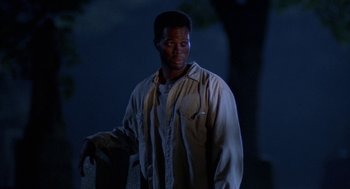 Movie still from “Tales from the Hood” (1995), directed by Rusty Cundieff – A man standing in the dark near a tree at night; Close Up shot, Low angle