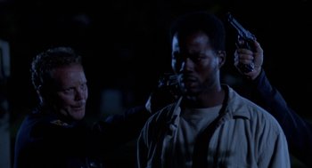 Movie still from “Tales from the Hood” (1995), directed by Rusty Cundieff – A man holding a gun while another man holds a gun; Close Up shot, Over the shoulder angle