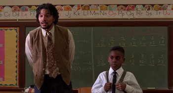 Movie still from “Tales from the Hood” (1995), directed by Rusty Cundieff – A man standing next to a young boy in a classroom; Medium shot, Over the shoulder angle