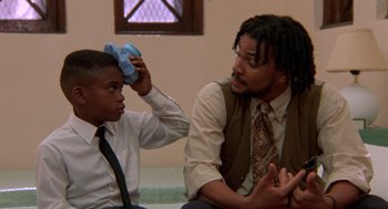Movie still from “Tales from the Hood” (1995), directed by Rusty Cundieff – A man and a young boy sitting next to each other; Close Up shot, Low angle