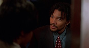 Movie still from “Tales from the Hood” (1995), directed by Rusty Cundieff – A person wearing a suit and a tie; Close Up shot, Over the shoulder angle