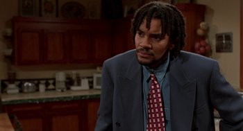 Movie still from “Tales from the Hood” (1995), directed by Rusty Cundieff – A man with dreadlocks wearing a suit and tie; Medium shot, High angle