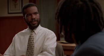 Movie still from “Tales from the Hood” (1995), directed by Rusty Cundieff – A man wearing a white shirt and a brown tie; Close Up shot, Over the shoulder angle