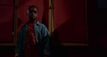 Movie still from “Tales from the Hood” (1995), directed by Rusty Cundieff – A young boy standing in a room with red walls; Medium shot, Low angle