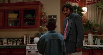 Movie still from “Tales from the Hood” (1995), directed by Rusty Cundieff – A man and a boy in a kitchen; Medium shot, Over the shoulder angle