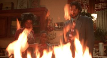 Movie still from “Tales from the Hood” (1995), directed by Rusty Cundieff – A man , woman , and child standing in front of a fire; Medium shot, Low angle