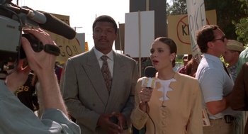 Movie still from “Tales from the Hood” (1995), directed by Rusty Cundieff – A man and a woman standing next to each other holding microphones; Close Up shot, Low angle