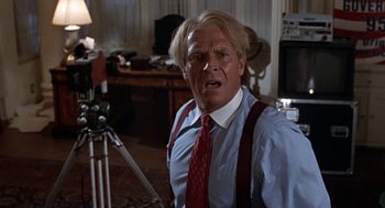 Movie still from “Tales from the Hood” (1995), directed by Rusty Cundieff – A man with blonde hair wearing a red neck tie; Close Up shot, Over the shoulder angle