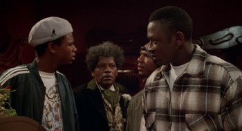 Movie still from “Tales from the Hood” (1995), directed by Rusty Cundieff – A group of people standing next to each other in a room; Medium shot, Over the shoulder angle