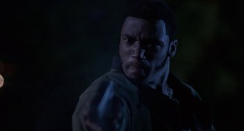 Movie still from “Tales from the Hood” (1995), directed by Rusty Cundieff – A man holding a gun in a dark room at night; Close Up shot, Low angle