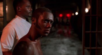 Movie still from “Tales from the Hood” (1995), directed by Rusty Cundieff – A man with a black face and a white beard; Close Up shot, Over the shoulder angle