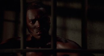 Movie still from “Tales from the Hood” (1995), directed by Rusty Cundieff – A man in a jail cell looking through bars; Close Up shot, High angle