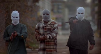 Movie still from “Tales from the Hood” (1995), directed by Rusty Cundieff – A group of people with masks on standing on a street; Wide shot, Low angle