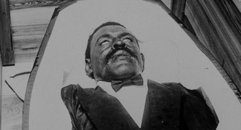 Movie still from “Tales from the Hood” (1995), directed by Rusty Cundieff – An old black and white photo of a man in a suit; Close Up shot, Overhead angle