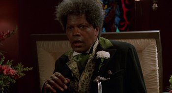 Movie still from “Tales from the Hood” (1995), directed by Rusty Cundieff – A man in a black jacket and a green tie; Close Up shot, Low angle