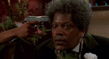 Movie still from “Tales from the Hood” (1995), directed by Rusty Cundieff – A man with a gun in his hand is holding a gun; Close Up shot, Over the shoulder angle